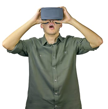 Young man in shirt enjoys and amazed by virtual reality glasses in front of white isolated background