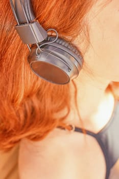 Cute red head woman listening to music at sunny day