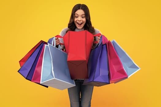 Amazed teenager. Funny teen girl hold shopping bag enjoying sale isolated on yellow. Portrait of teenager schoolgirl is ready to go shopping. Excited teen girl