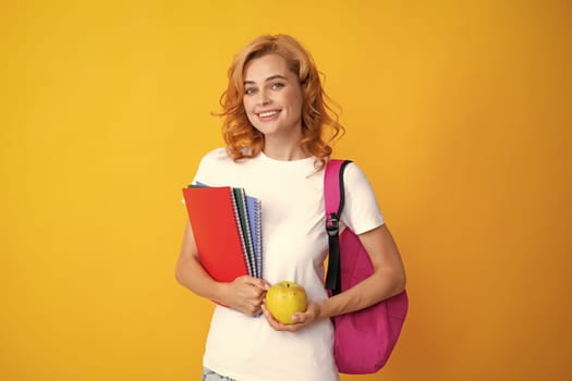 Cute student woman with backpack holds some documents and books over yellow background. Portrait of smiling young woman student in shirt backpack hold notebooks. Education in high school university college
