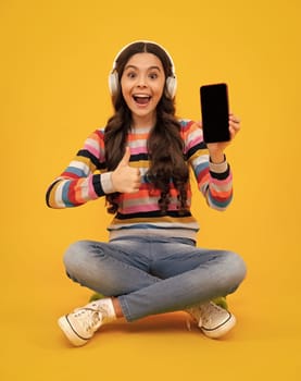 Amazed teenager. Teenager child girl holding smartphone. Hipster girl types text message on cell phone, enjoys online communication, types feedback, Kid showing blank screen mobile phone, mockup