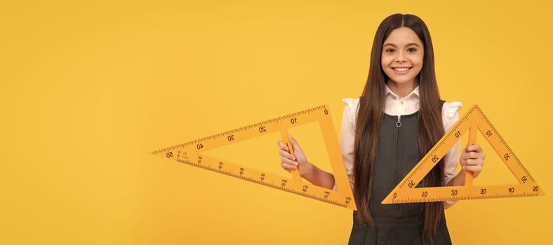 cheerful teen girl hold math triangle ruler in school on yellow background, education. Banner of school girl student. Schoolgirl pupil portrait with copy space