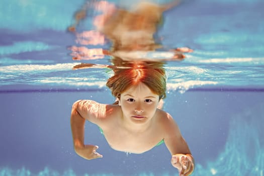 Child boy swimming underwater in swimming pool. Funny kids boy play and swim in the sea water