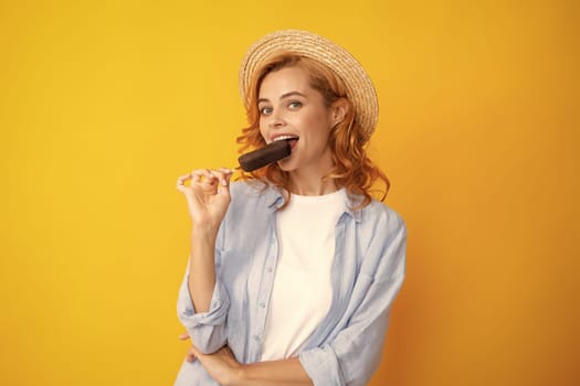 Portrait of cheerful funny teenage girl enjoys eating cold frozen dessert, eats delicious chocolate ice cream, yellow background