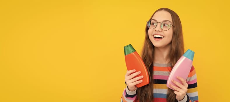 kid in glasses holding shower gel. happy teen girl use shampoo bottle. child with hair conditioner. Banner of child girl hair care, studio poster header with copy space