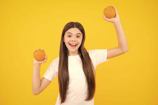 Excited teenager portrait. Teenage girl holding a grapefruit on a yellow background. Amazed girl