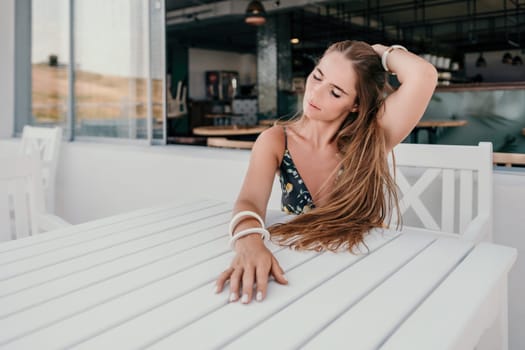 Happy woman portrait in cafe. Boho chic fashion style. Outdoor photo of young happy woman with long hair, sunny weather outdoors sitting in modern cafe