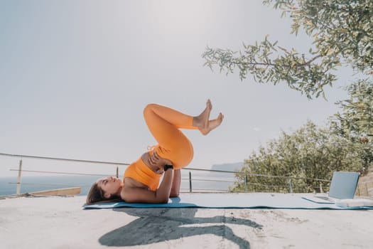 Fitness woman sea. Outdoor workout on yoga mat in park near to ocean beach. Female fitness pilates yoga routine concept. Healthy lifestyle. Happy fit woman exercising with rubber band in park.