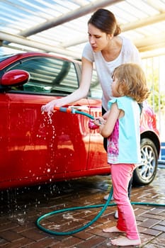 Mom, girl and washing car with teaching or learning for child development, growth and childhood memories. Parent, kid and enjoy with bonding, fun and educational with support and recreational at home.