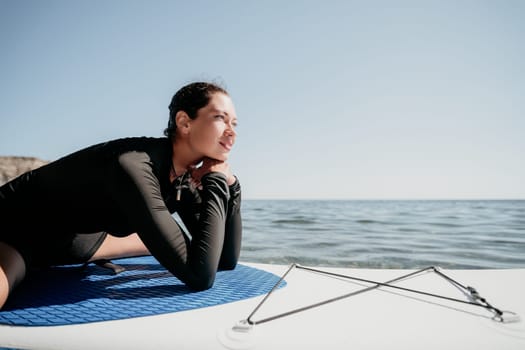 Woman sup yoga. Middle age sporty woman practising yoga pilates on paddle sup surfboard. Female stretching doing workout on sea water. Modern individual hipster outdoor summer sport activity