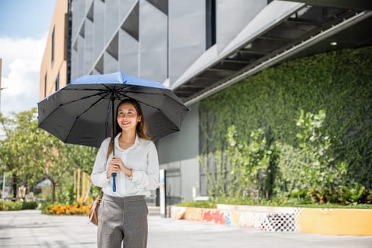 Under the hot sun, a young Asian businesswoman walks to work holding an umbrella. Her stern expression and professional attire reflect her determination and success in the business world.