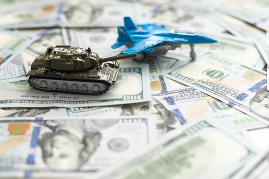 Toy tank on US hundred dollar bills banknotes close up. The concept of war costs, military spending and economic crisis. High quality photo