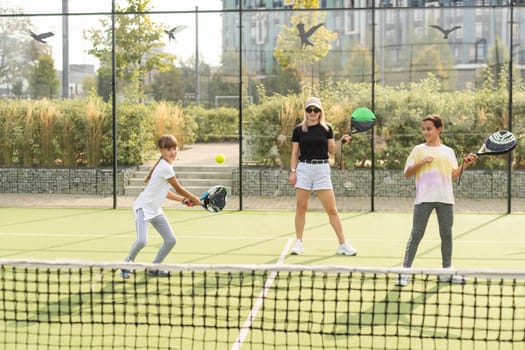 Cheerful coach teaching child to play tennis while both standing on tennis court. High quality photo