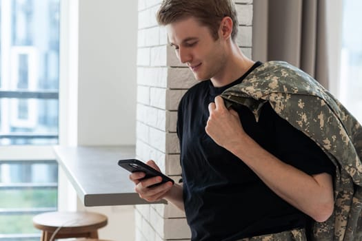 Young army man using smartphone at home.