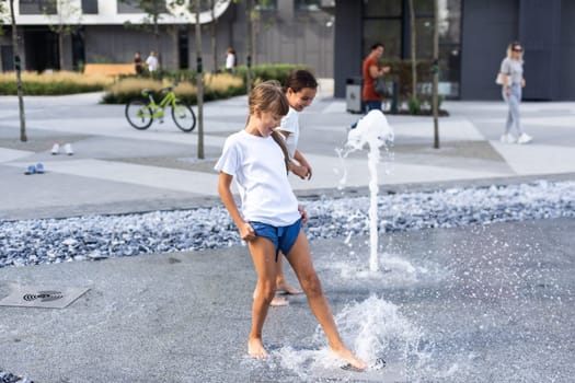 Cute young sisters playing in fountains. Children having fun with water on sunny summer day. Active leisure for kids. High quality photo