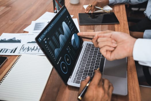 Multiracial analyst team use BI Fintech software to analyze financial data on meeting table. Financial dashboard data display on laptop screen with analyzed chart for marketing indication. Concord