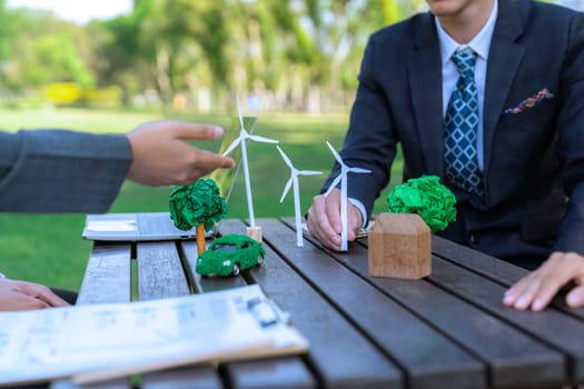 Group of asian business people presenting environmentally friendly development plan and sustainable technology project for greener future, establishing outdoor eco business office at natural park.Gyre