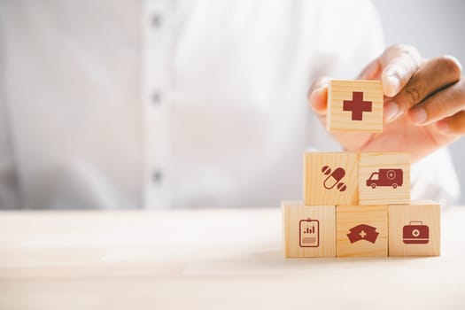 Captured moment, Hand grips wooden block with healthcare and medical icons. Portrays safety, health, and family well-being, symbolizing pharmacy, heart care, and happiness. health care concept