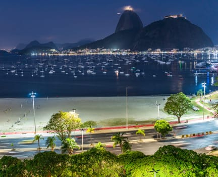 Evening bay scene with lit boats, urban skyline, and glowing roads.