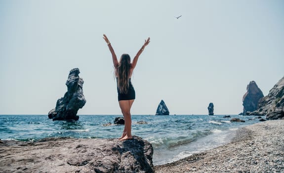 Woman travel sea. Young Happy woman in a long red dress posing on a beach near the sea on background of volcanic rocks, like in Iceland, sharing travel adventure journey