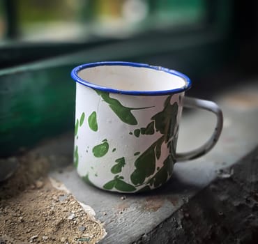 Ice chocolate drink on a vintage Indonesian iron mug with random green pattern called Blirik cup or cangkir Blirik on bokeh background along with chocolate filling bread on a cafe in Bogor