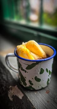 Ice chocolate drink on a vintage Indonesian iron mug with random green pattern called Blirik cup or cangkir Blirik on bokeh background along with chocolate filling bread on a cafe in Bogor