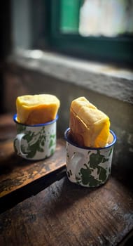 Ice chocolate drink on a vintage Indonesian iron mug with random green pattern called Blirik cup or cangkir Blirik on bokeh background along with chocolate filling bread on a cafe in Bogor