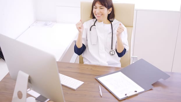 Female doctor celebrating good news that she is observing on the computer screen