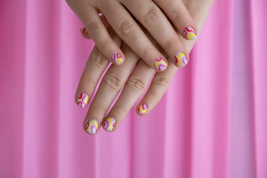 Pastel softness colorful manicured nails on pink background. Woman showing her new summer manicure in colors of pastel palette. Simplicity decor fresh spring vibes earth-colored neutral tones design