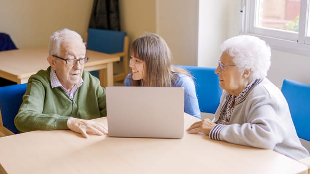 Granddaughter helping to her grandparents to use the laptop in geriatric