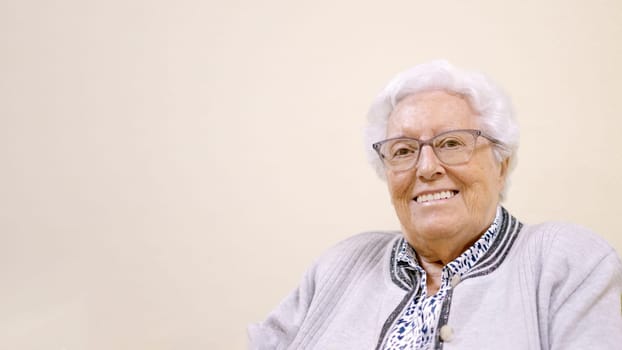 An elder smiling woman looking at camera sitting in geriatric with copy space