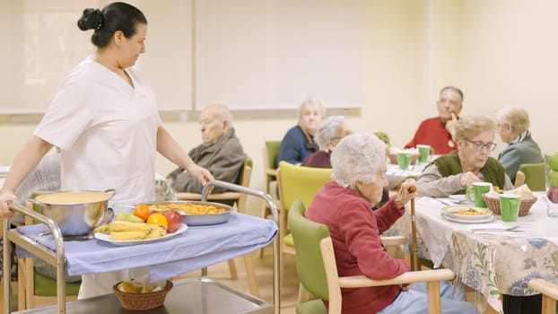 Female cook entering with food to the dining room of geriatric