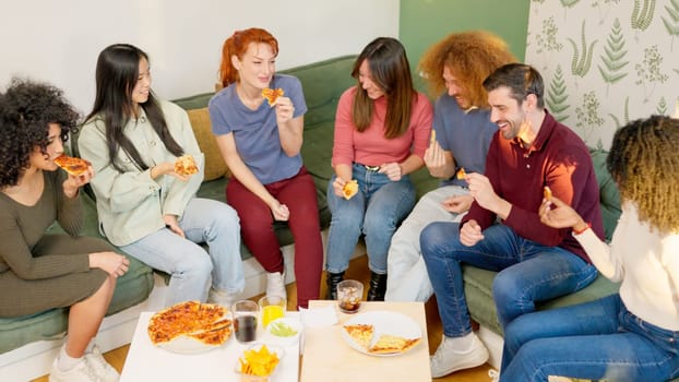 Multi-ethnic young adult friends eating pizza and talking at home
