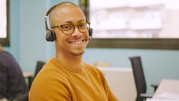 Smiling hispanic man using headset while working in a coworking