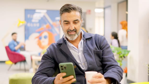 A mature employee using phone in modern coworking