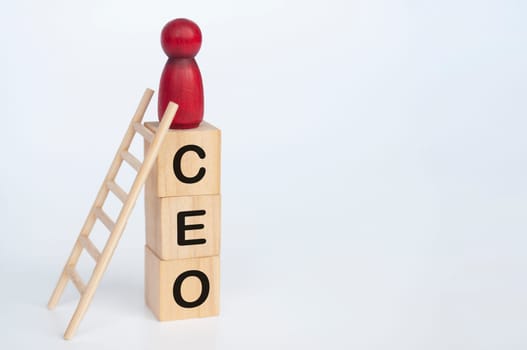 Red doll figure on top of wooden cubes with CEO text. Leadership and success concept.