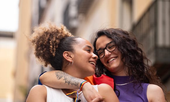 Headshot of two multiethnic lesbian women in love hugging and smiling enjoying time together.