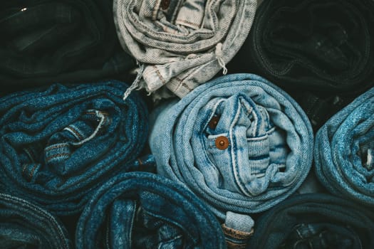 Background from stack of different color rolled jeans. Roll blue denim jeans arranged in stack. Recycling old blue jeans. Zero waste. High quality photo