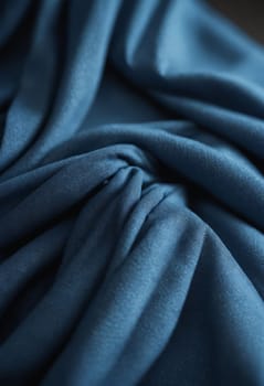 A close up of a sleeve made from electric blue satin fabric with tints and shades. The pattern contrasts against the darkness, perfect for sportswear or elegant events