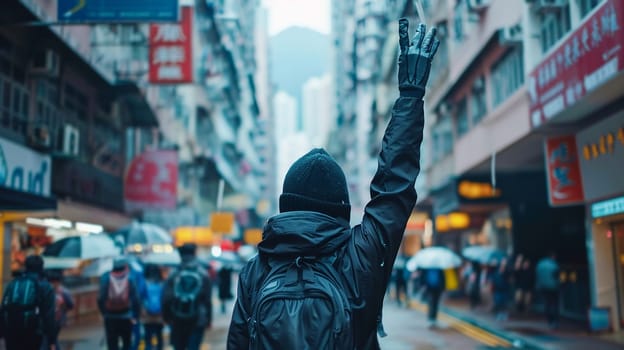 Lone protester with raised hand stands against urban backdrop, crowd in motion behind, cityscape surrounds scene amid demonstration