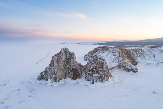 Aerial shot of a Shamanka rock on Olkhon island at sunset. Winter landscape. Popular touristic destination. Natural landmark. Panoramic view.