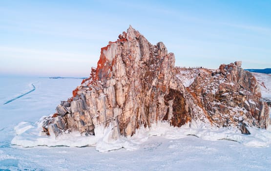 Aerial shot of a Shamanka rock on Olkhon island at sunset. Winter landscape. Popular touristic destination. Natural landmark. Panoramic view.