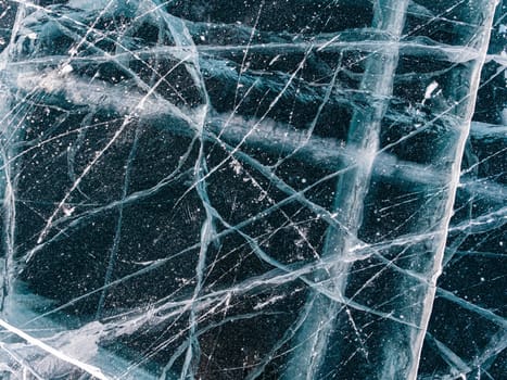 Aerial top down view on the blue cracked ice of the lake Baikal. Winter landscape, frozen lake. Ice kingdom.