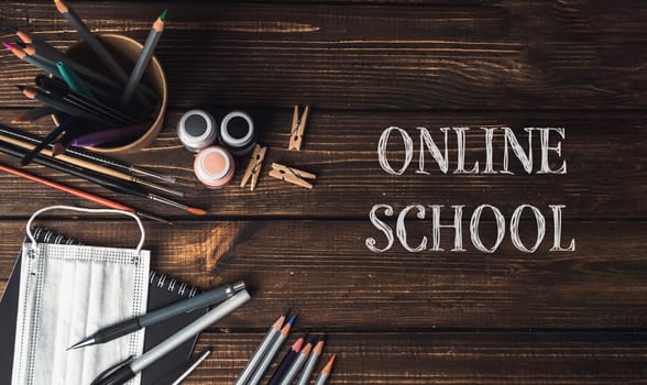 A wooden table with a bowl of pencils, a bottle of nail polish, and a pair of scissors. The words online school are written on the table