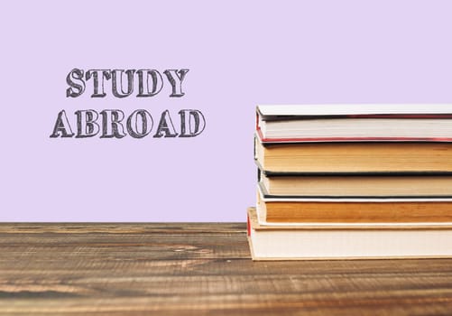 A stack of books with the word study abroad written on top. The books are piled on top of each other, creating a sense of importance and knowledge. Concept of learning and education