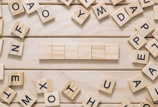 A wooden board with a crossword puzzle on it. The puzzle is made up of wooden blocks and the letters are scattered around the board