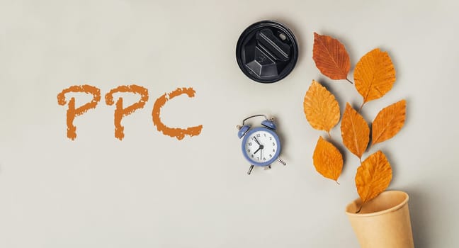 A clock is on a table with a leafy plant and the word ppc written in orange