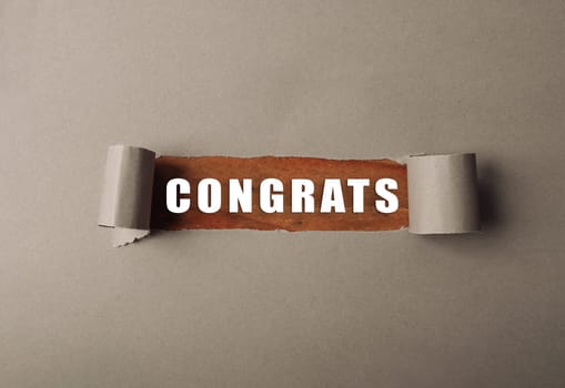 A torn piece of paper with the word congratulations written on it. The image has a sense of celebration and achievement