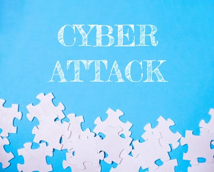 A blue background with white jigsaw puzzle pieces scattered on it. The word cyber attack is written in white on the background