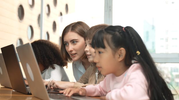 Smart teacher teaching and looking student using laptop at classroom. Professional instructor explained about programing engineering code or prompt while studying and learning program. Erudition.